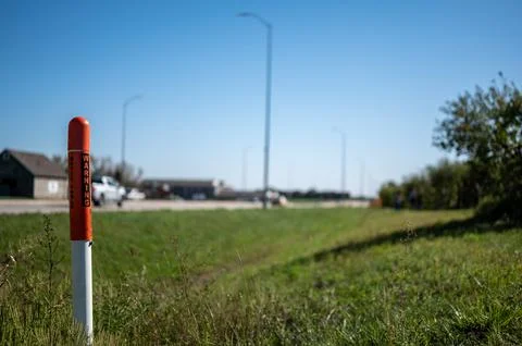 Marker post for underground internet optics line along a road ditch. Stock Photos