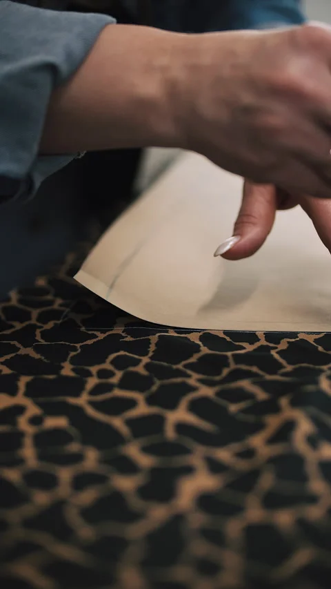 Marking fabric with chalk on leopard print textile Stock Footage 308724322
