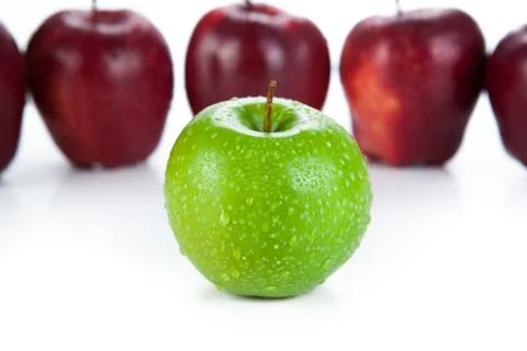 Maroon apples lined up in a row and green apple closeup Stock Photos