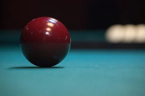 Maroon ball lying on a green pool table. the time before the game. the reflec Stock Photos