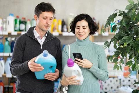 Married couple checking expiration date of detergent using smartphone Foto stock
