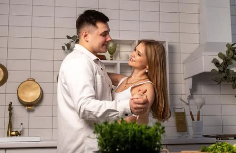 Married couple dancing in kitchen. Smiling husband and wife looking at each Stock Photos