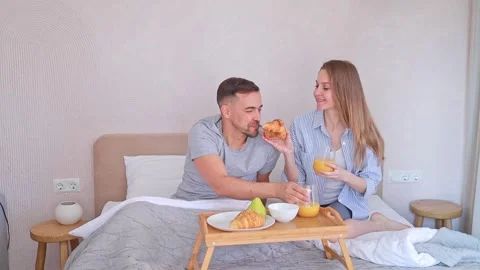 Married couple enjoying romantic breakfast in bed in the morning at home with Stock Footage 310075665