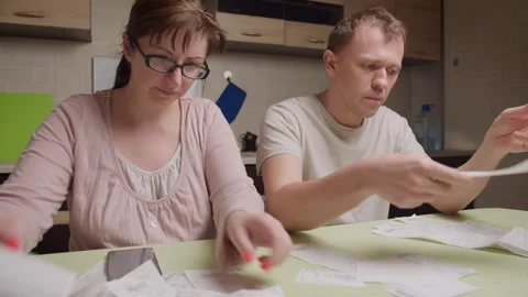 A married couple in the evening sitting at the table looks through the checks Stock Footage 149043479