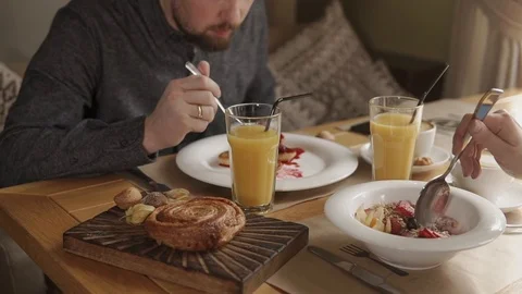 Married couple is having breakfast in a cafe, eating porridge and pancakes Stock Footage 87952325