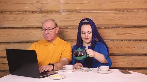 A married couple at home at the table working at the computer and drinking tea 库存影片 145848322
