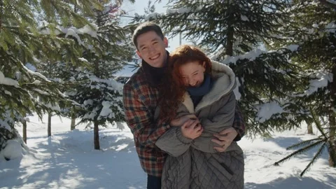 A married couple hugging while standing in the middle of a snowy park. A man Stock Footage 237439696