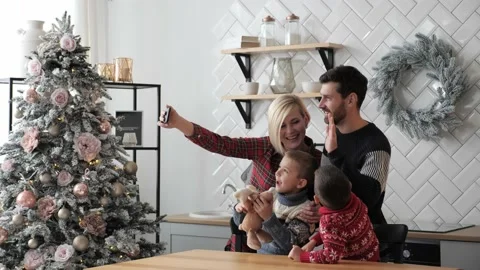 Married couple with kids using mobile phone talking to family Merry Christmas. Stock Footage 142662379