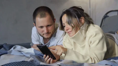 Married couple lies in bed using smartphones. Couple Of spouses lying on bed Video stock 128546124
