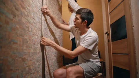A married couple makes repairs in their house, neatly gluing wallpaper Vidéo 146041167