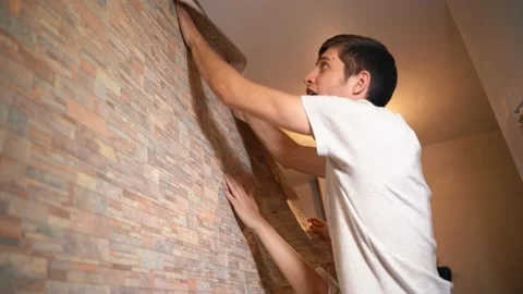 A married couple makes repairs in their house, neatly gluing wallpaper Vidéo 146041638