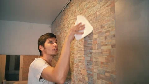 A married couple makes repairs in their house, neatly gluing wallpaper Vidéo 146041722