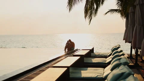 Married couple relaxing by the ocean at sunset Stock Footage 242748645