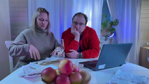 A married couple sits at a white kitchen table in the evening light with a glass Stock Footage 306014369