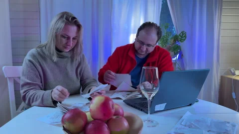 A married couple sits at a white kitchen table in the evening light with a glass Stock Footage 306014433