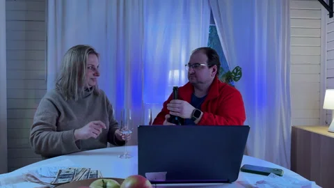 A married couple sitting at a white kitchen table in the evening light with a gl Stock Footage 306014916