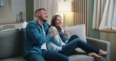 A married couple spends time sitting on the couch, hugging and have fun talking Stock Footage 141613806