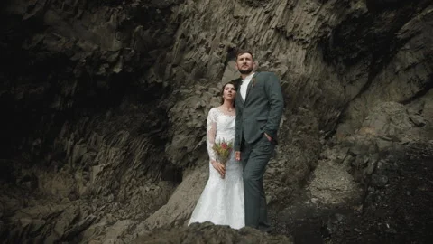 Married couple standing in rocks thoughtfully, Reynisfjara beach, Iceland Stock Footage 253690741