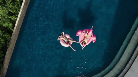 Married couple sunbathing swim with inflatable pink flamingo toy mattress Stock Footage 257539666