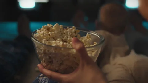 A married couple takes salted corn popcorn from a bowl, creating a movie the Stock Footage 323706187
