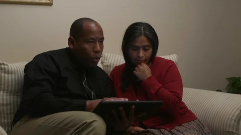 Married Couple Using and Electronic Tablet While Sitting on Sofa Stock Footage 110905785