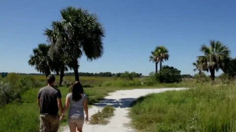 Married couple walking away down a tropical path holding hands Stock Footage 8765230