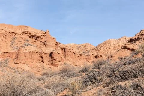 Mars Canyon red sandstone cliffs and desert shrubs under clear blue sky Stock Photos