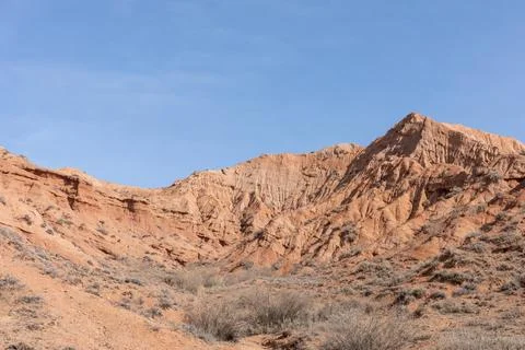 Mars Canyon red sandstone cliffs and arid landscape under blue sky, Kyrgyzstan Stock Photos