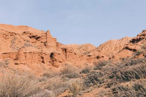Mars Canyon red sandstone cliffs and desert shrubs under clear blue sky Stock Photos