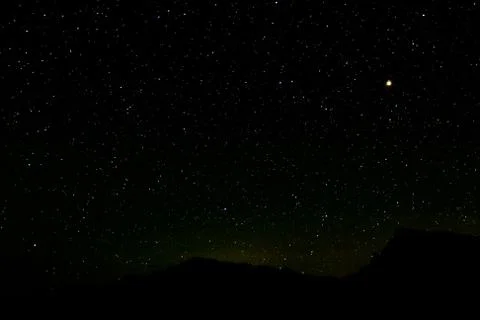 Mars in transit at zenith in star filled sky over silhouetted moutains Stock Photos