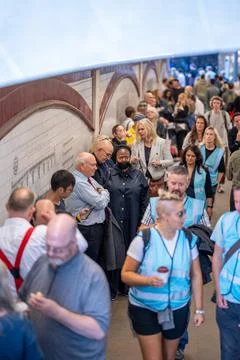 Marshals walking past a large queue of people along the South Bank of the Riv Stock Photos