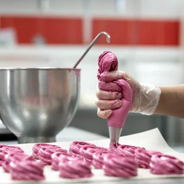 Marshmallow cooking process. Chef squeezing pink meringues dessert from pastry Stock Photos