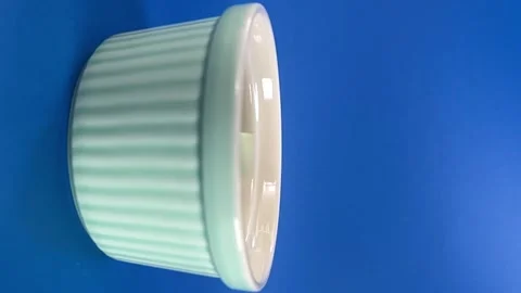 Marshmallow dropping into ceramic ramekin against blue background in slow motion Stock Footage 340810092