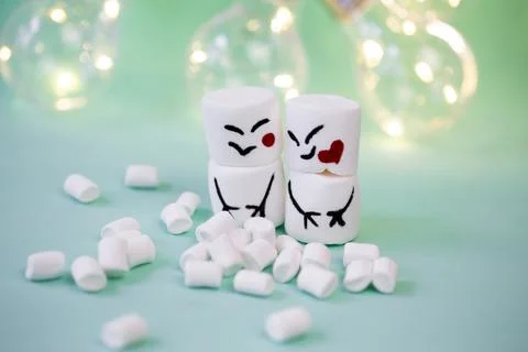 Marshmallow men on a mint turquoise background illuminated by a garland Stock Photos