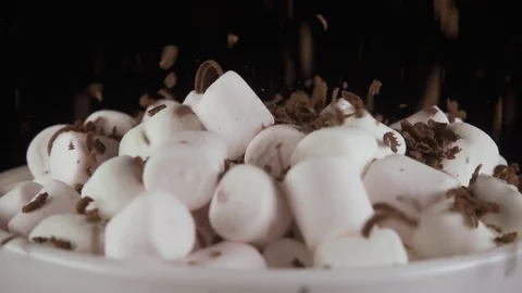 Marshmallow sprinkle with grated chocolate on a black background. Slow motion Stock Footage 75312918