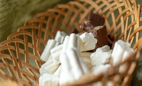 Marshmallows and chocolate lie in the same wicker basket Stock Photos