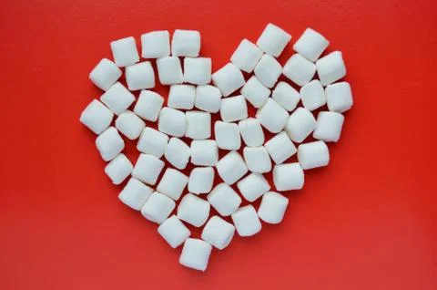 Marshmallows on red background. Marshmallows laid out in the shape of a heart Stock Photos