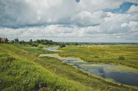 Marshy river flows through the field Stock Photos