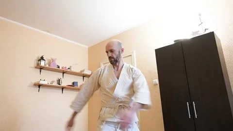 Martial artist practicing karate movements in home environment interior Stock Footage 345638203