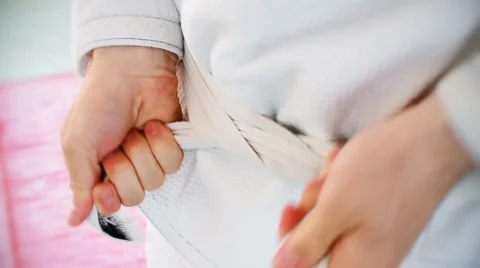 Martial arts Man Tying the Knot to his White Belt on White Uniform. Stock Footage 59085296