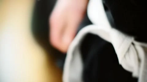 Martial arts Man Tying the Knot to his White Belt on Black Uniform. Jujitsu Stock Footage 59085297