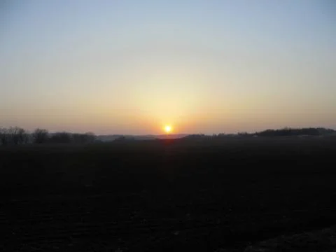 Marvelous sunset over dark fields under bright sky. Stock Photos