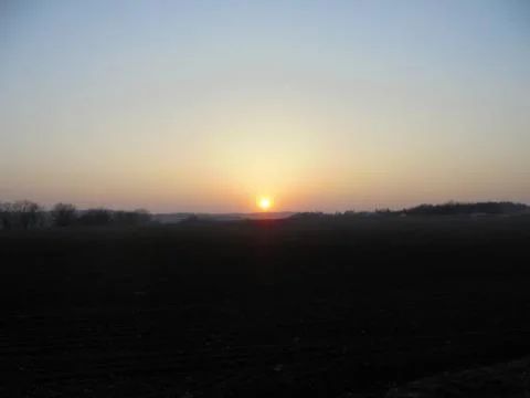 Marvelous sunset over dark fields under bright sky. Stock Photos