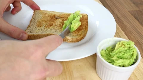 Mashed Avocado Being Spread On Brown Toast Stock-Footage 135468250