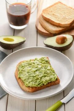 Mashed avocado toast. Breakfast served on wooden table Stock Photos