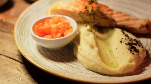 Mashed potato and grilled salmon steak with herbs on ceramic plate, close-up 스톡 동영상 107777911