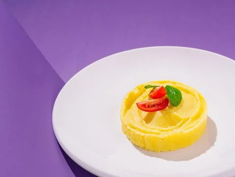 Mashed potato with tomato and basil served on a white plate Stock Photos