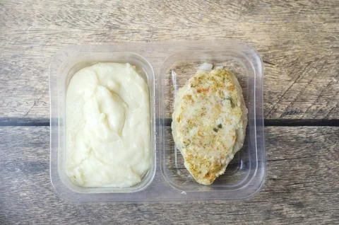Mashed potatoes and chicken cutlet presented in separate plastic containers.. Stock Photos