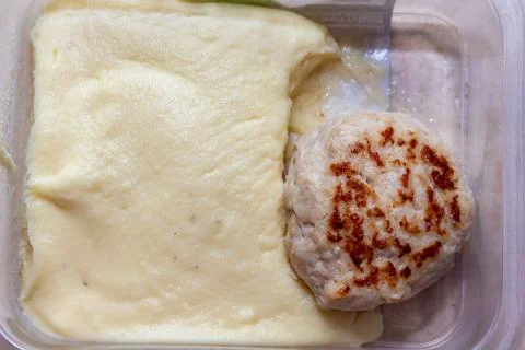 Mashed potatoes and fried meat patty in plastic container for takeaway meal Stock Photos