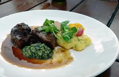 Mashed potatoes and short beef ribs in bbq sauce on white plate against woode Stock Photos